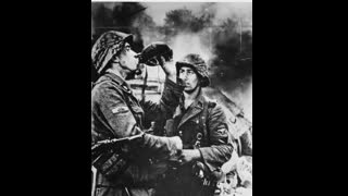 Two Waffen SS soldiers have a drink. In the background burns a T-34 tank